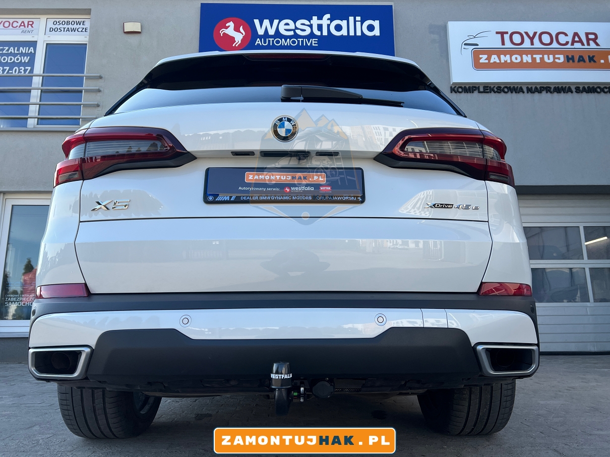 na zdjeciu biale nowe bmw x5 g05 45e zbliżenie na tyl samochodu z hakiem holowniczym na tylnym zderzaku marki westfalia 